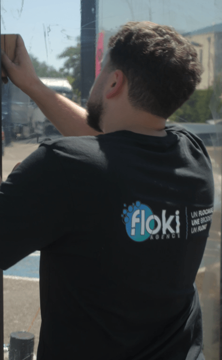 Pose d'un film solaire pour vitrine par la société Floki. technicien avec le tee-shirt Floki